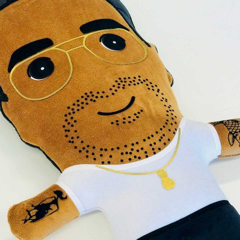 Een knuffelportretje van een papa met zwart haar, een licht bruine huid, stoppels, gouden bril, twee tattoos en een pinda ketting.